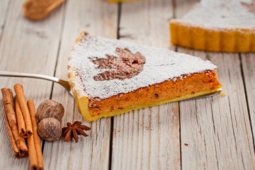 A piece of autumn pumpkin pie on white wooden rustic background. Selective focus. Close up