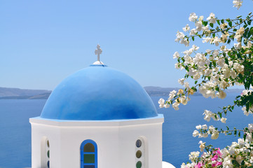Fototapeta na wymiar Blue domed church overlooking the Aegean Sea at Oia - Santorini Island in Greece.