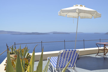 White umbrella on Terrace overlooking Caldera of Santorini and and Aegean sea in Greece.