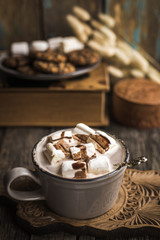 Cup of hot cocoa with marshmallow on cutting board