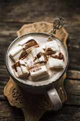 Cup of hot cocoa with marshmallow on cutting board