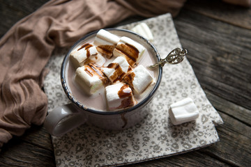 Cup of hot cocoa with marshmallow on cutting board