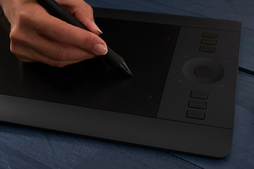 hand draws a black professional graphics tablet