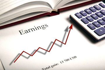 table with earnings with digits, calculator and diagram