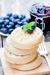 Hot  toasted crumpets on the wooden table with blueberries and j