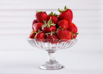 Fresh strawberries in a glass vase on a white background. Vegetarian and healthily cooking concept.selective focus.