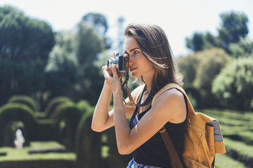 Hipster girl with backpack using vintage photo camera close up, copy space of blank empty mockup,...