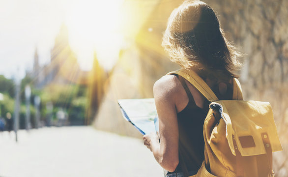 Hipster young girl with backpack using and looking at map. Said view tourist traveler enjoying on background panoramic sun city. Person visiting the sights Barcelona in holiday. Mockup for text 