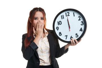 Sleepy young Asian business woman with a clock in the morning.
