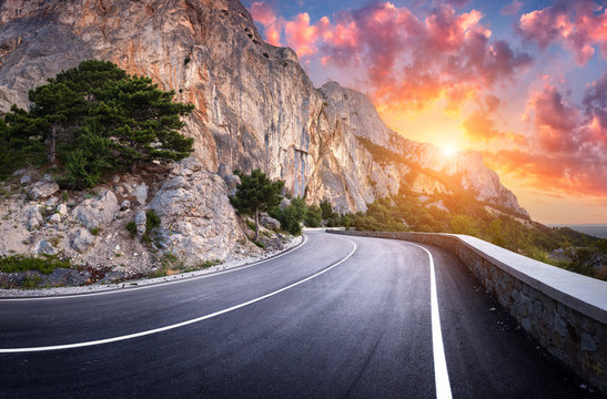 Asphalt road. Landscape with beautiful winding mountain road with a perfect asphalt in the evening. High rocks, amazing sky at sunset in summer. Panoramic. Travel background. Highway at mountains