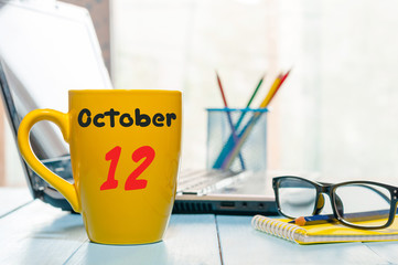 October 12th. Day 12 of month, Hot tea cup with calendar on insurance agent workplace background....