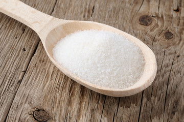 Sugar in spoon on wooden table