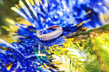 Золотое кольцо на новогодней елке, украшенной гирляндами и елочными шарами. © Valeriia