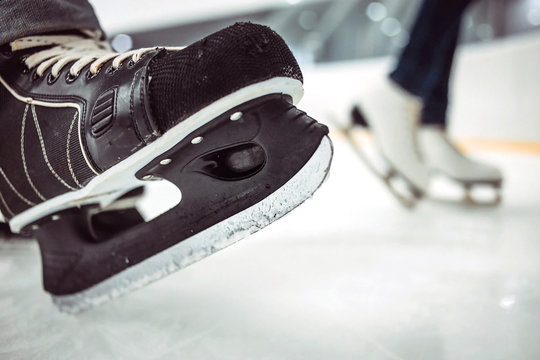 Man's hockey and women' figure skates on ice background. Closeup of blades.