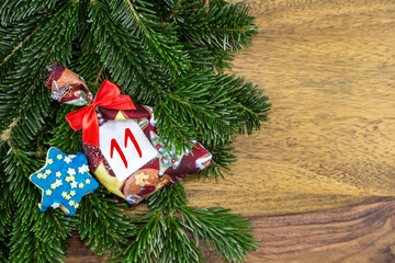 ein Weihnachtssäckchen und ein blauer Stern liegen auf Tannenzweigen