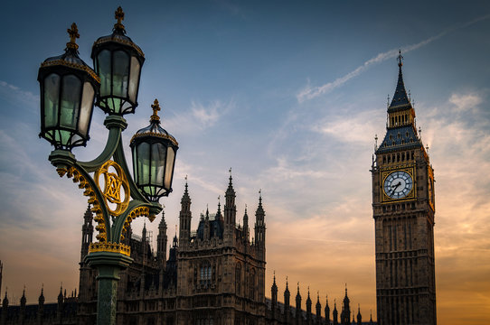 Big Ben, The Houses of Parliament and a lamppost from the Westminster bridge at sunset on a cloudy summer evening in London, England, UK