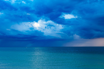 Blue clouds over the ocean at sunset with a storm