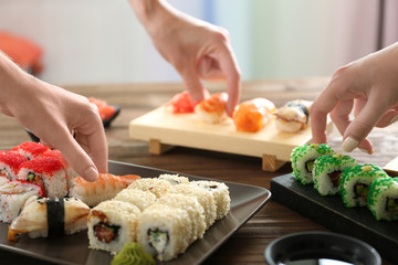 Hands taking delicious sushi on table