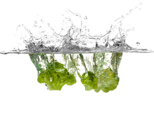 Broccoli falling into water on white background