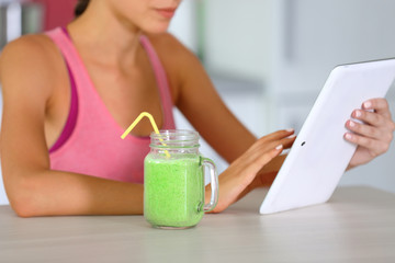 Fototapeta na wymiar Girl with tablet and smoothie calculating calories on kitchen