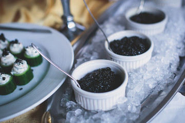 A concept of luxury wealthy life with sparkling champagne in glass and black caviar with ice on a catering table
