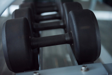 Obraz na płótnie Canvas Close up at Rows of dumbbells in the gym. Sports dumbbells in modern sports club. Weight Training Equipment. Black dumbbells