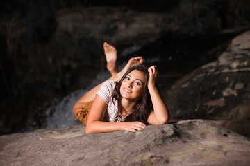 Caucasian teenage brunette girl laying on rocks at night