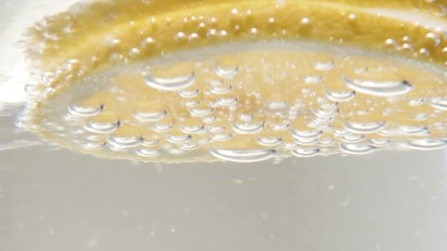 Lemon in carbonated water glass with ice cubes refreshing beverage close-up 4K 2160p 30fps UltraHD footage - Citrus fruit slice in cooled down tonic drink 3840X2160 UHD video 