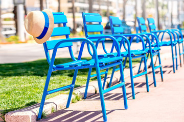 The blue chairs of the promenade with hat in Cannes city. This chairs are iconic symbol and tourist...