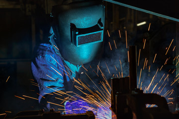 Worker welding automotive part in factory