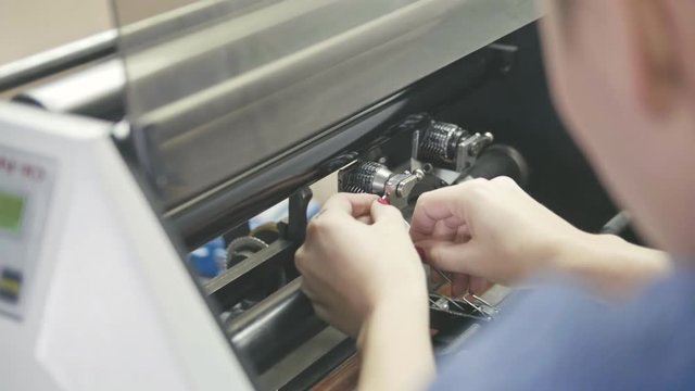 Woman with red nails repair the printing machine, polygraph industry