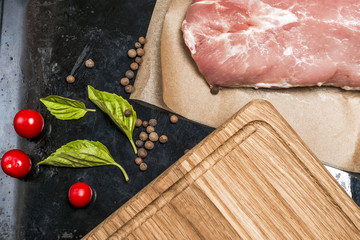 Fresh meat selection on black background with spices in a white bowl