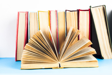 Open book, stack of colorful hardback books on light table. Back to school. Copy space for text