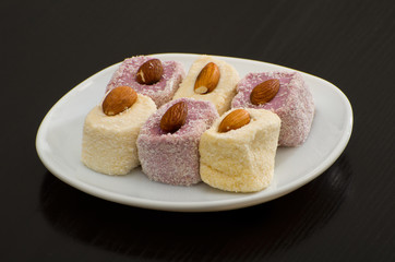 White and purple Turkish Delight with almonds on a white dish, black background