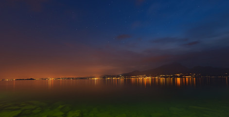 Lago di Garda at night (Garda Lake), with the lights of the coast and starry sky, Italy