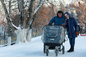 old man and woman walk with a stroller in the winter