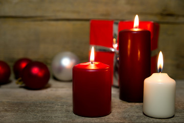 Fototapeta na wymiar Candles, christmas balls and a red gift on wooden table