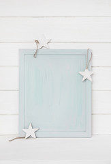Holz Hintergrund hellblau mit Sterne auf Hintergrund weiß mit Schild oder Bilderrahmen in blau türkis zur Dekoration.