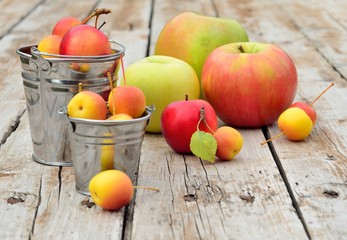 Variety of apples on a wooden table in small metal buckets. Selective focus