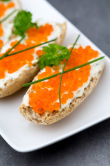 Red caviar on bread on white plate.