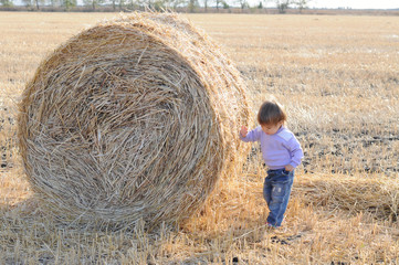 Little kids near sheaf of hay