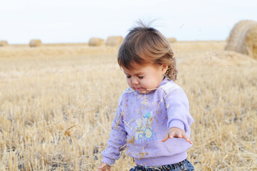 Naklejka na ściany i meble Little girl playing with hay