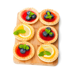set  of tasty tartlets with lemon and raspberry jam on wooden bo