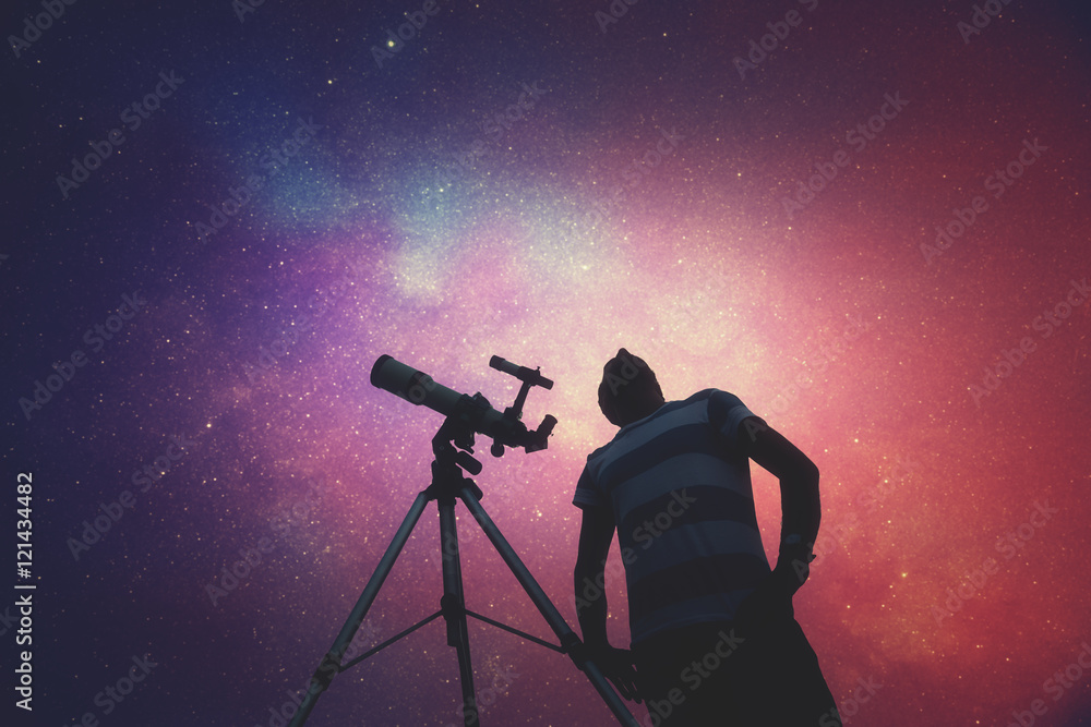 Wall mural man looking at the stars with telescope beside him.