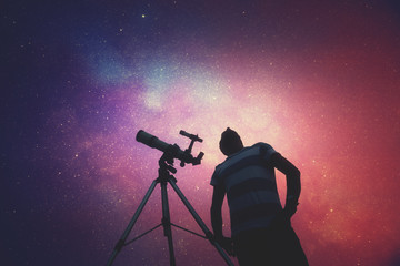 Man looking at the stars with telescope beside him. © astrosystem