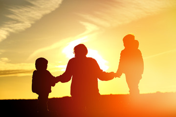 family travel - father and two kids walking at sunset