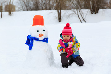 Fototapeta na wymiar little girl building snowman in nature