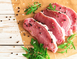 Fresh raw pork meat with salt, pepper and arugula.