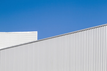 Fototapeta na wymiar Corrugated sheet metal wall and roof against blue sky. Modern warehouse or storage. Industrial look. Outdoor. Digital background