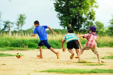 Fotobehang The boys are playing football in the sunshine day. © nateejindakum